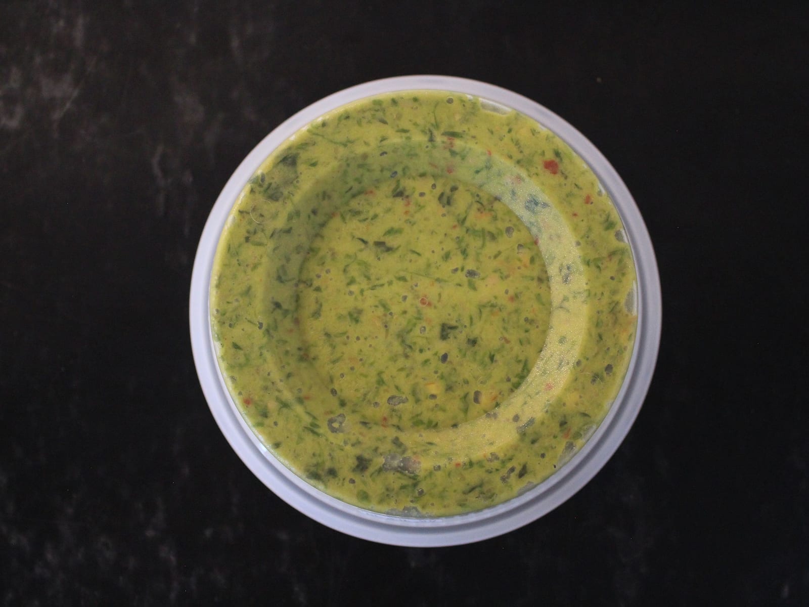 Open tub of vivid green Thai basil pesto