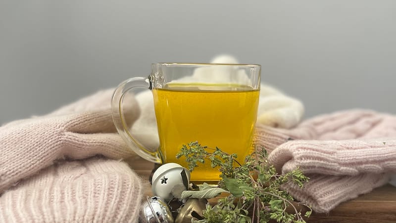 A mug of hot broth resting on knitwear